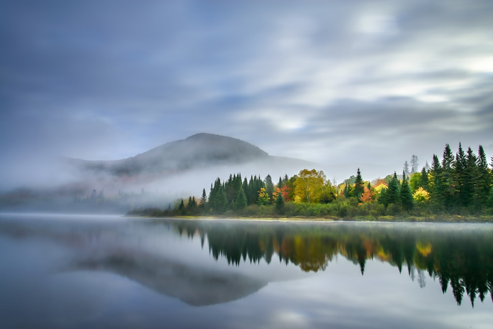 a lake surrounded by trees with a mountain in the background