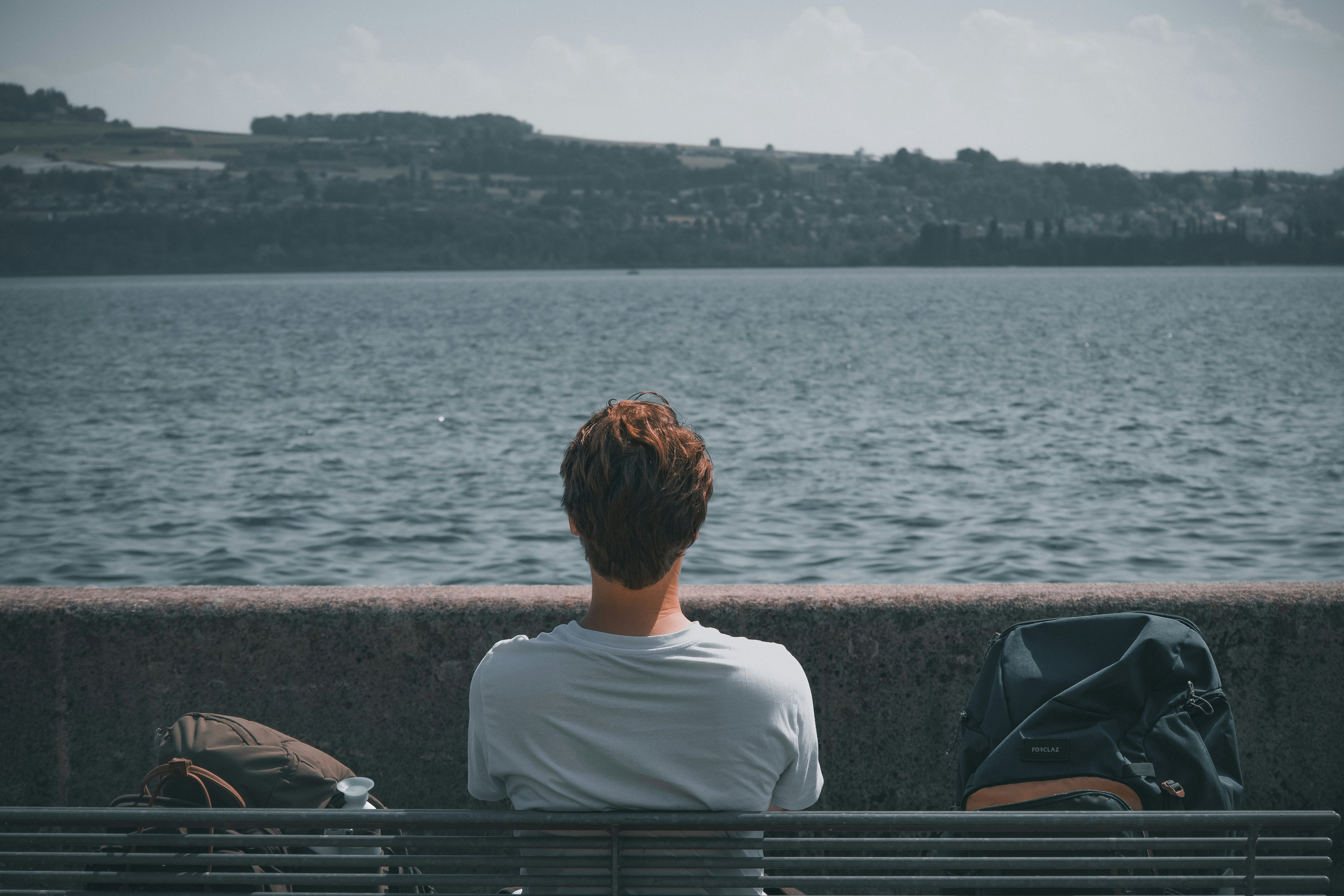 a person sitting on a bench next to a body of water