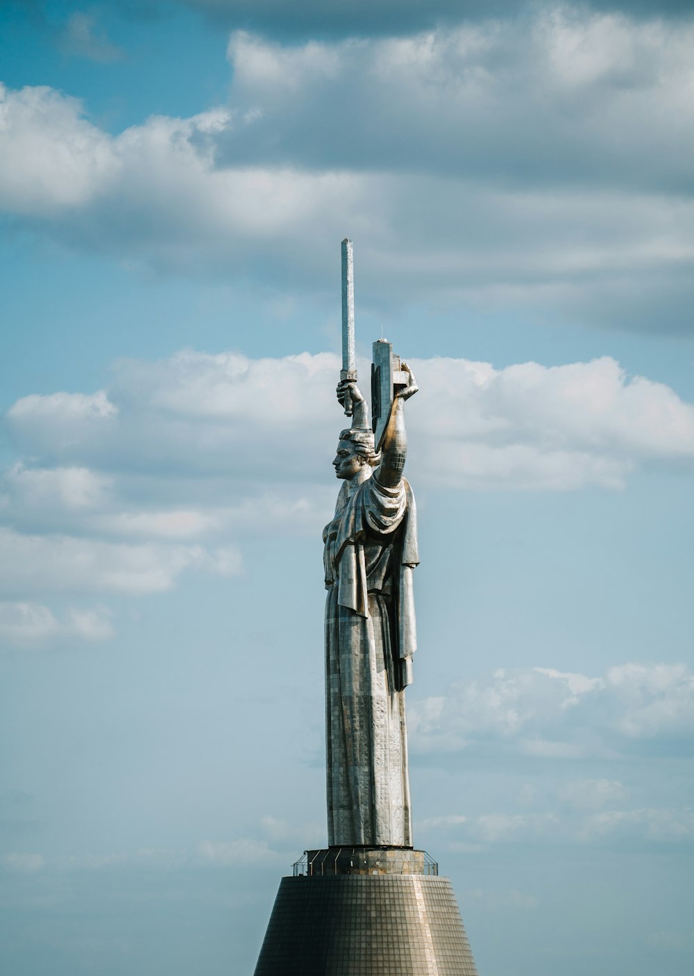 eine Statue einer Frau, die ein Kreuz auf dem Dach eines Gebäudes hält
