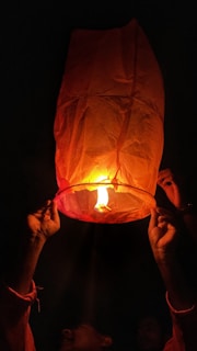 Close-up of a hand releasing a glowing ember into the night sky.