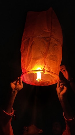Close-up of a hand releasing a glowing ember into the night sky.