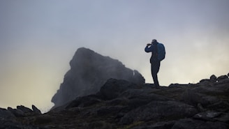 A candid photo of Siddhesh Shashikant Pingale standing on a rugged trail, wearing a backpack and looking thoughtfully into the distance under a soft morning light.