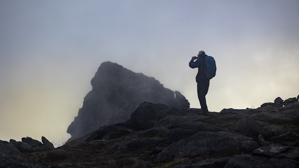 A candid photo of Siddhesh Shashikant Pingale standing on a rugged trail, wearing a backpack and looking thoughtfully into the distance under a soft morning light.
