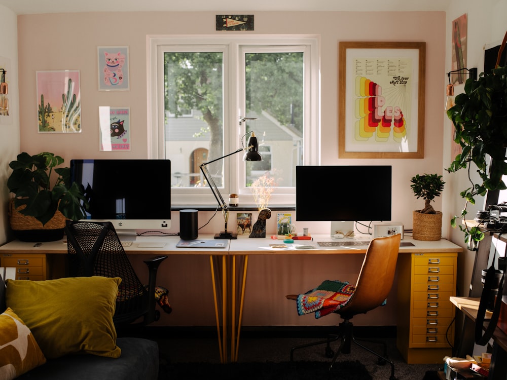 a desk with two computer monitors and a chair