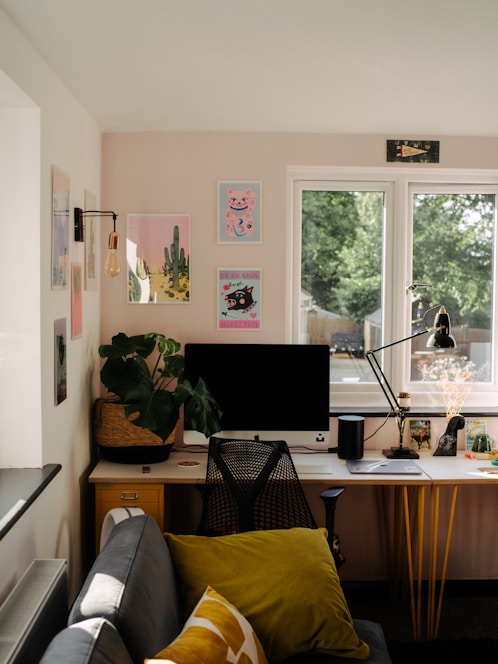 A cozy home office setup with architectural sketches and a laptop, sunlight streaming through a window.