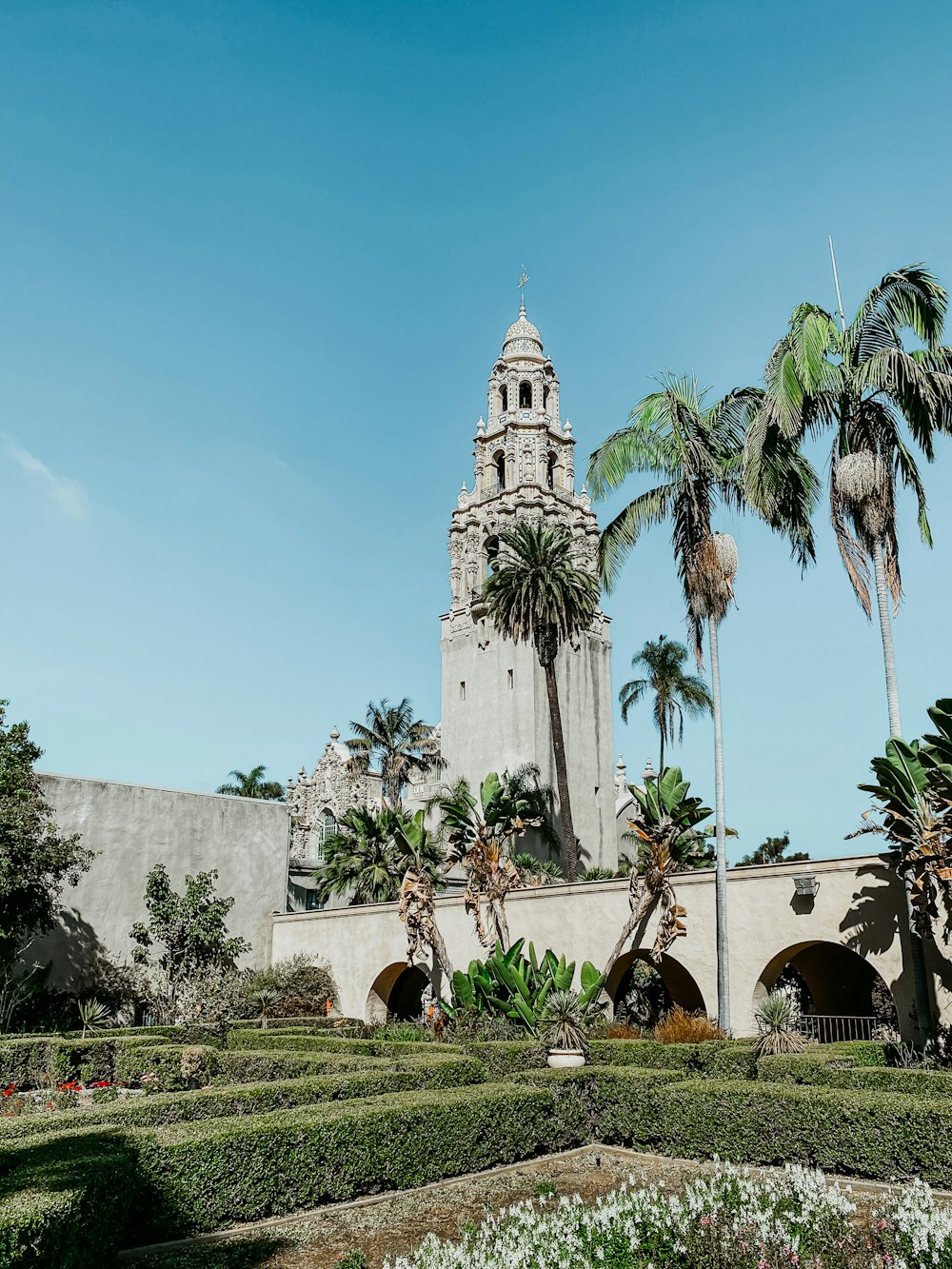 a large building with a clock tower in the middle of a garden