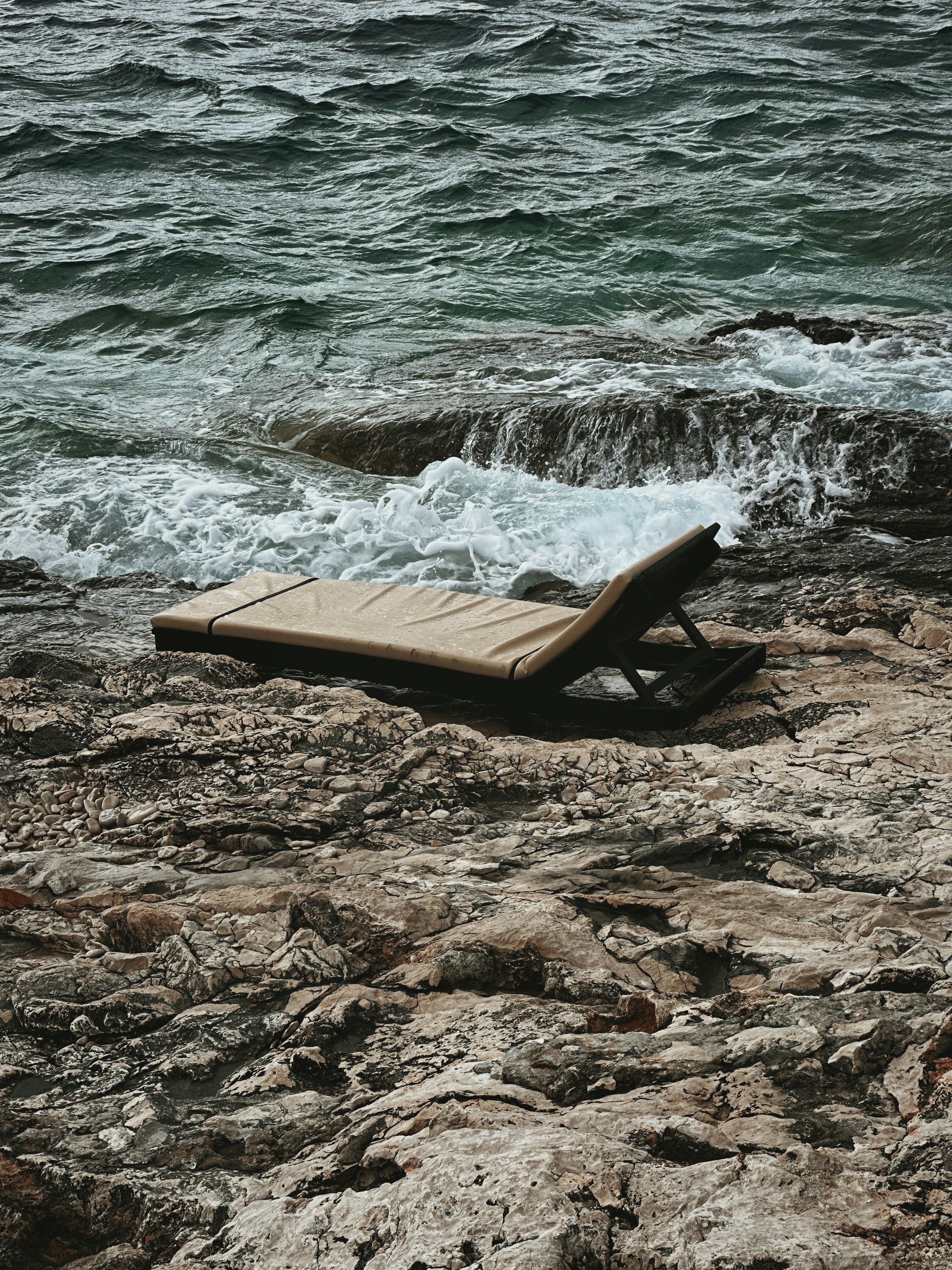 岩だらけのビーチの上に座っている木製のベンチ