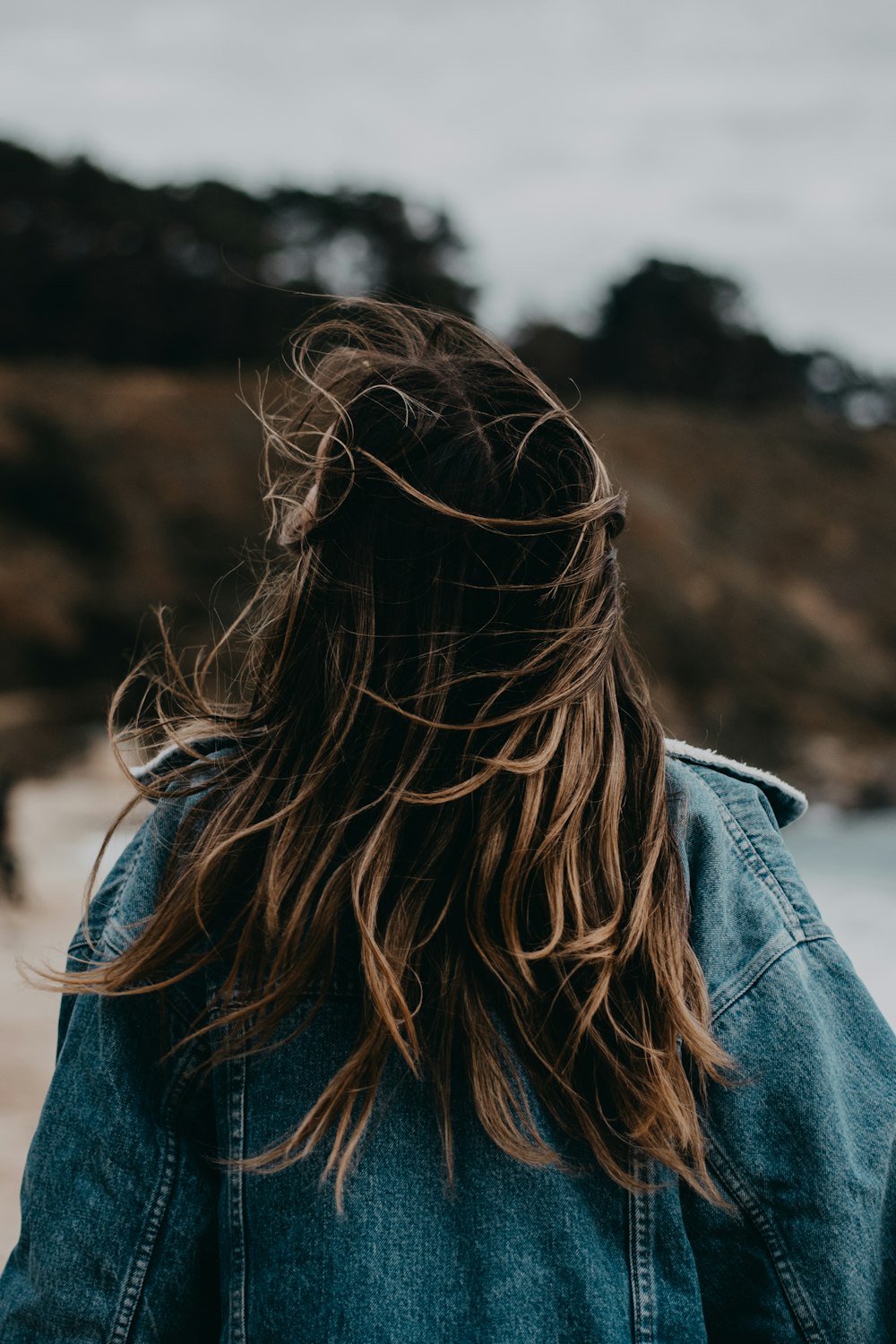 a woman with long hair walking on the beach