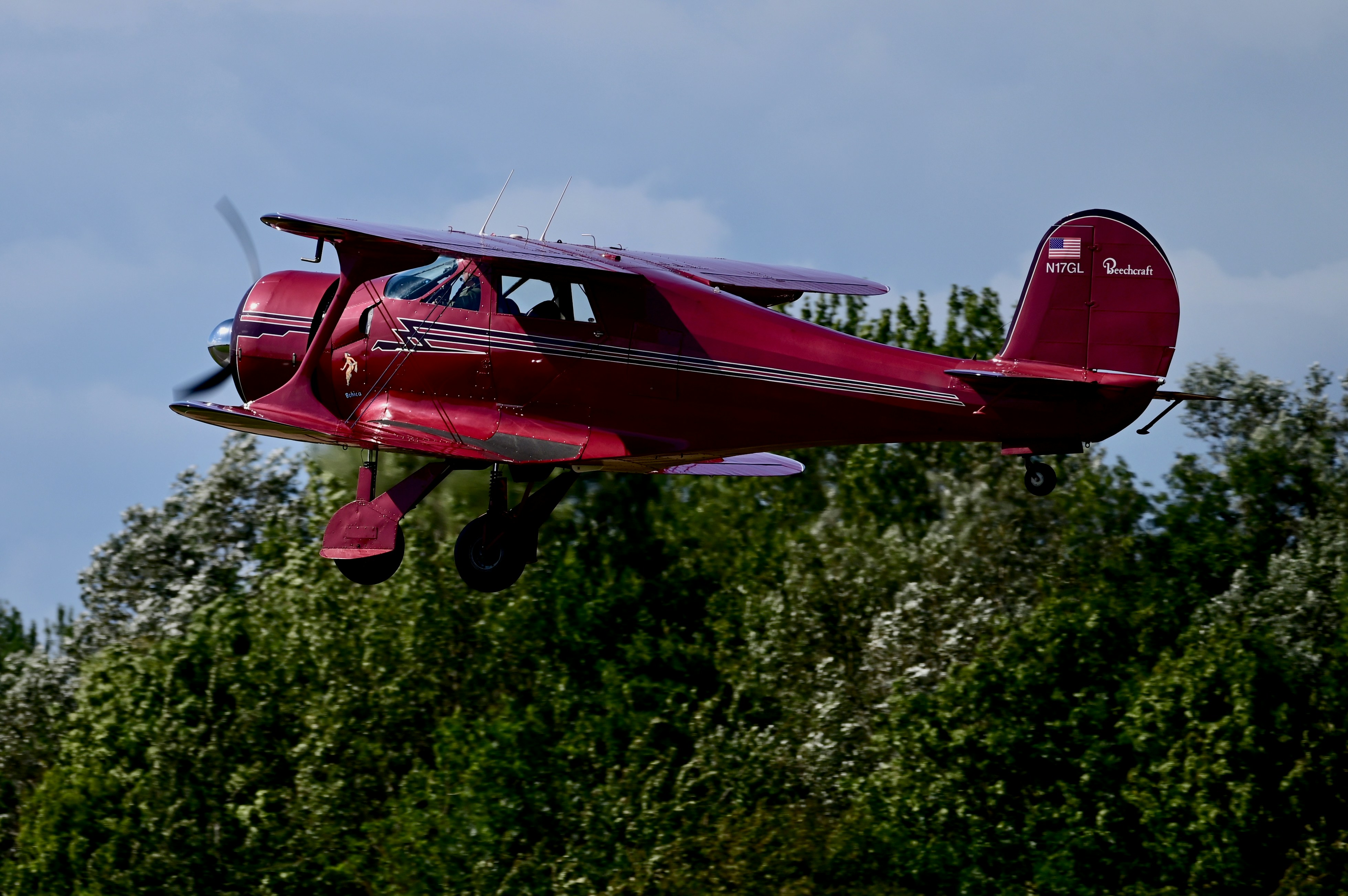 a small red airplane flying over a forest, 