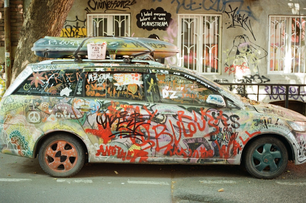a car covered in graffiti parked in front of a building