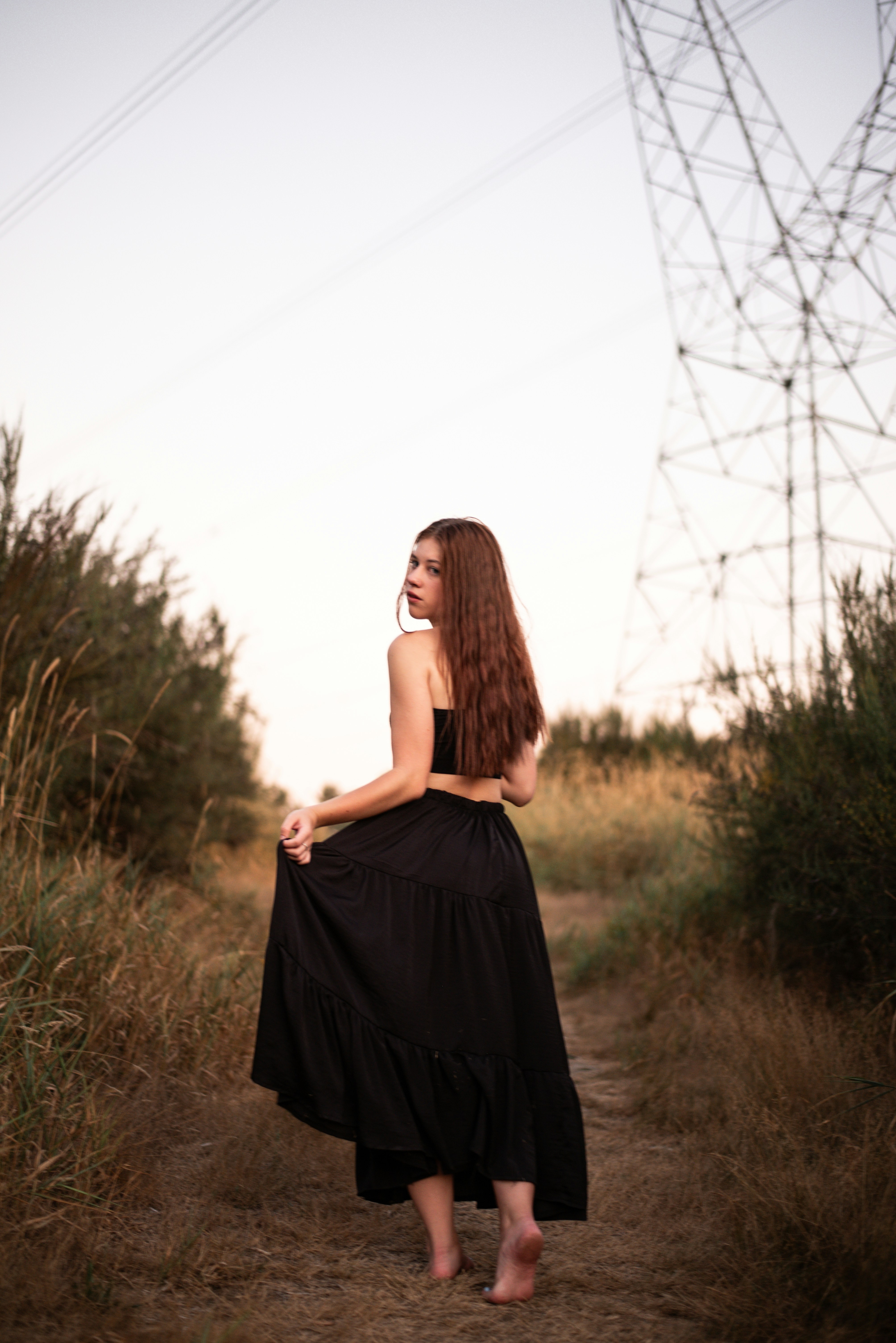 A woman in a black dress walking down a dirt road photo – Free ...