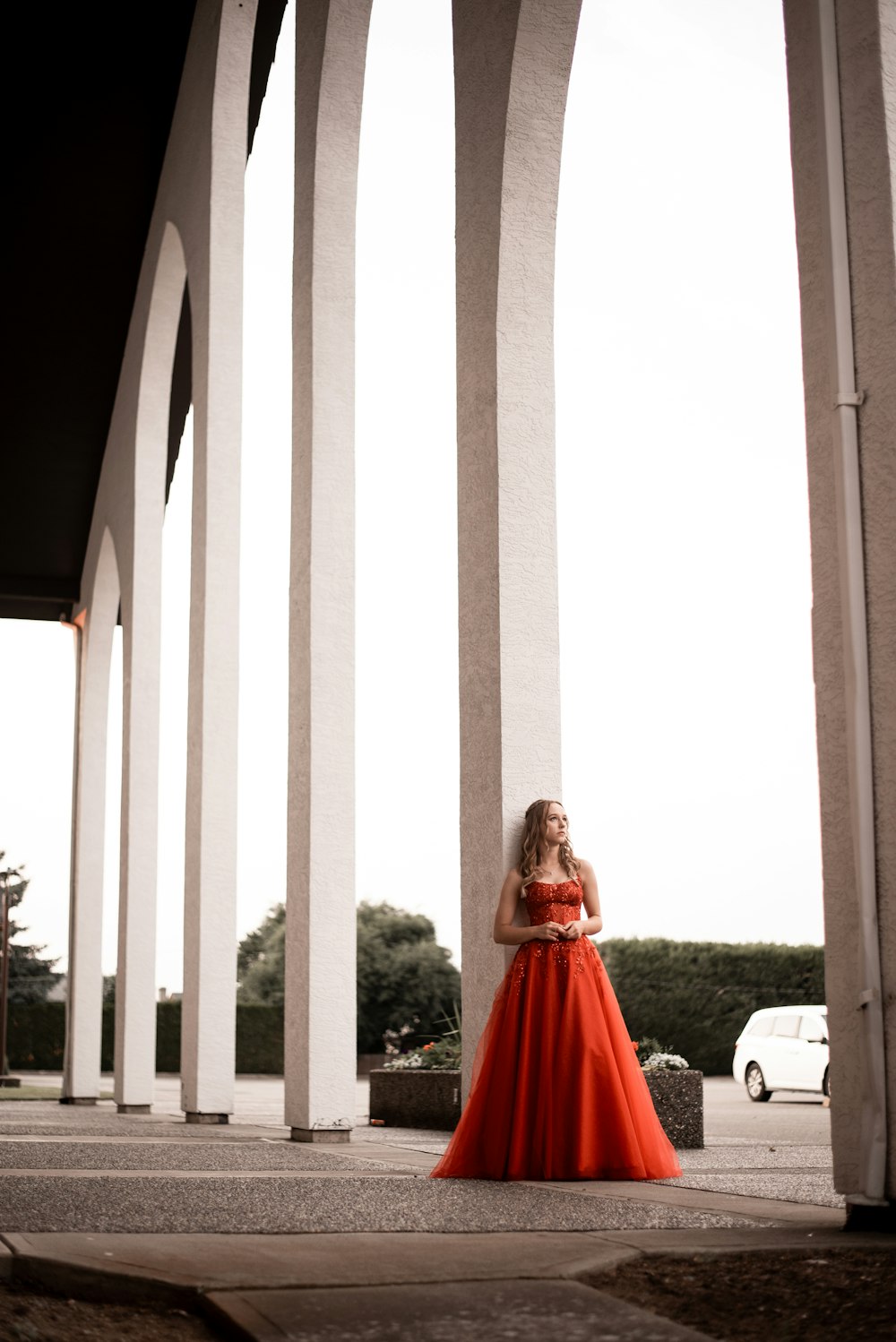 a woman in a long red dress standing in front of arches