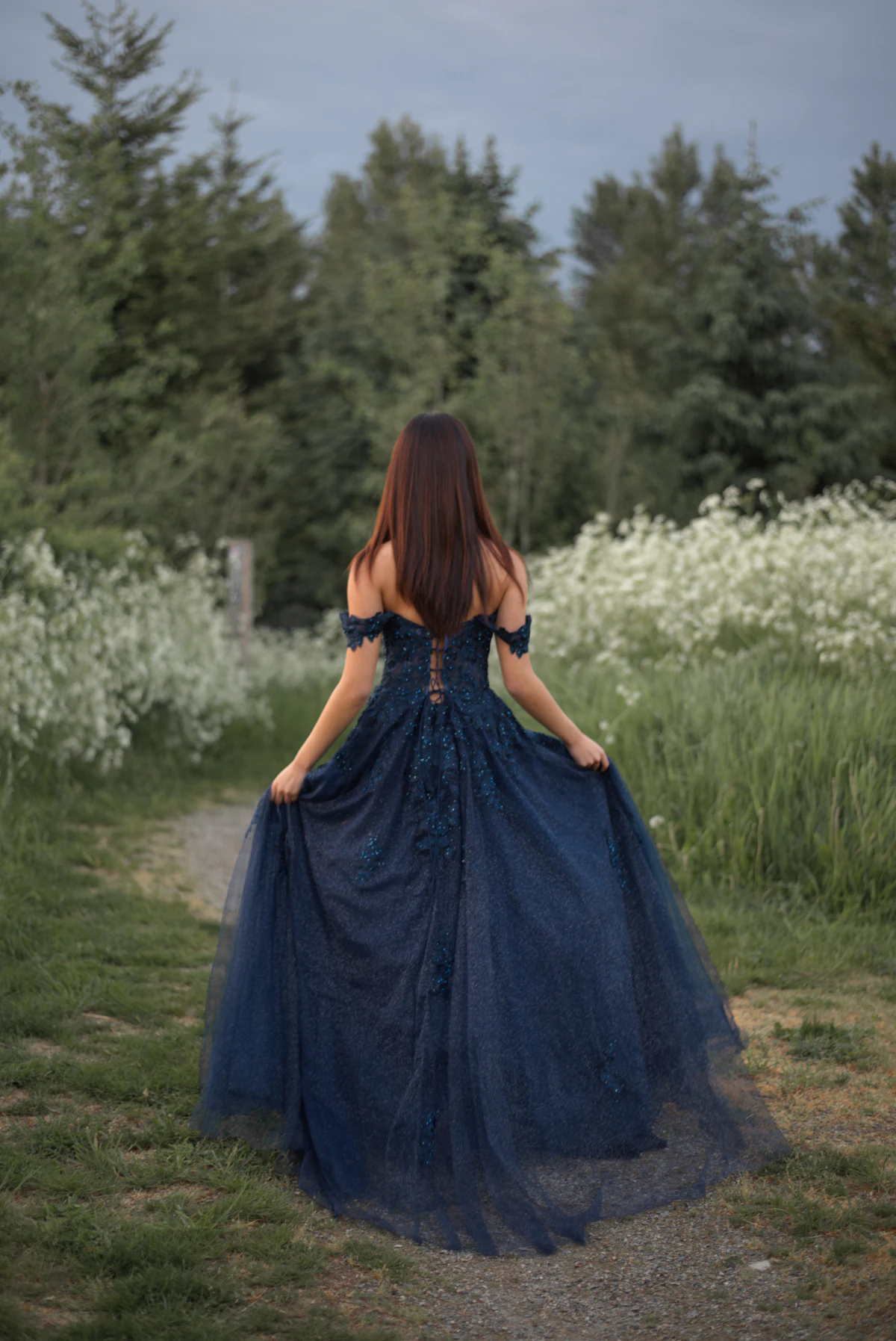 Woman in a navy tulle gown walking through a field