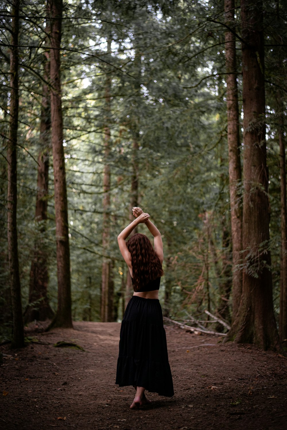 a woman standing in the middle of a forest