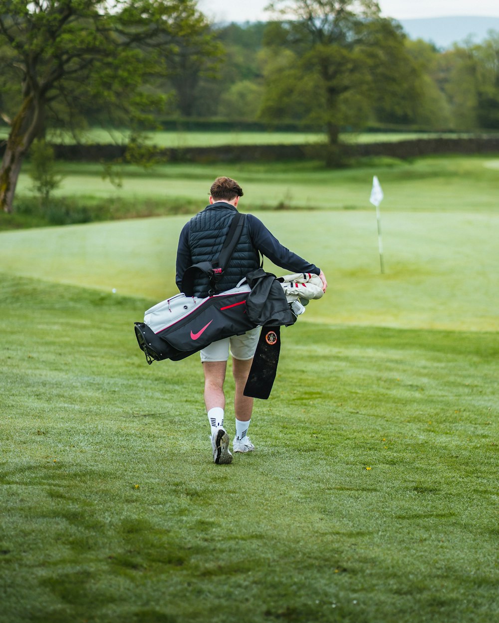 a man walking across a lush green golf course