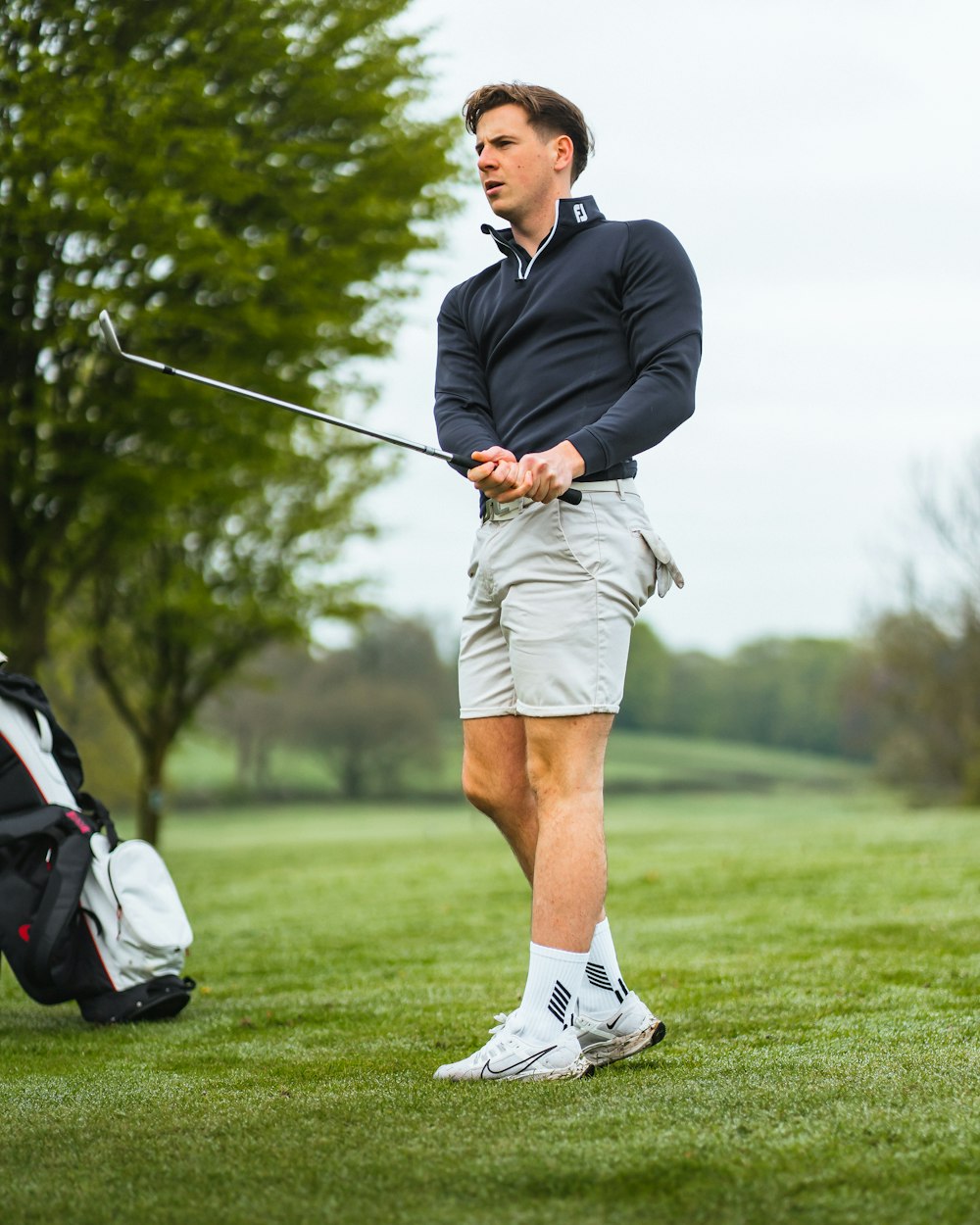 a man holding a golf club on top of a green field