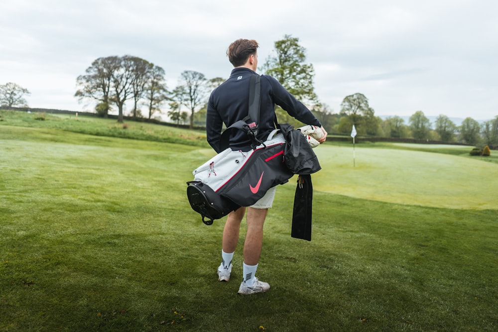 a man holding a golf bag on top of a lush green field