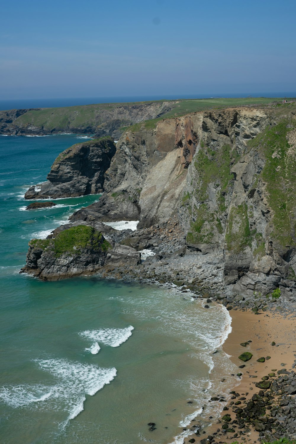 a sandy beach next to a rocky cliff