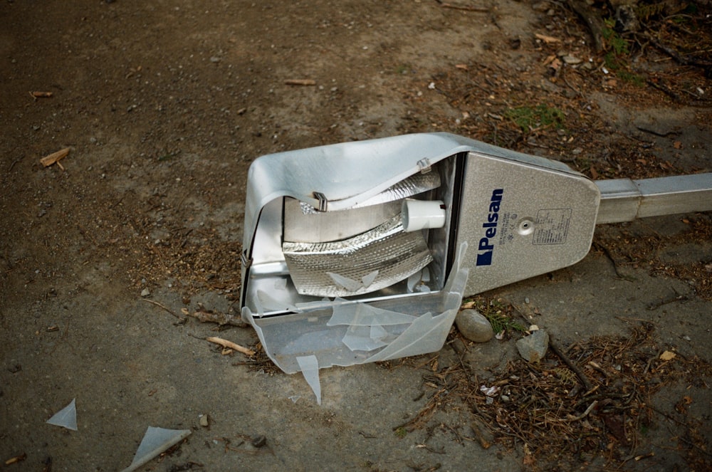 a trash can sitting on the side of a dirt road