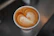 A beautifully crafted coffee latte with intricate heart-shaped latte art in a ceramic cup.