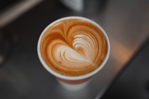 A cup of coffee with intricate latte art in the shape of a heart on a creamy surface.