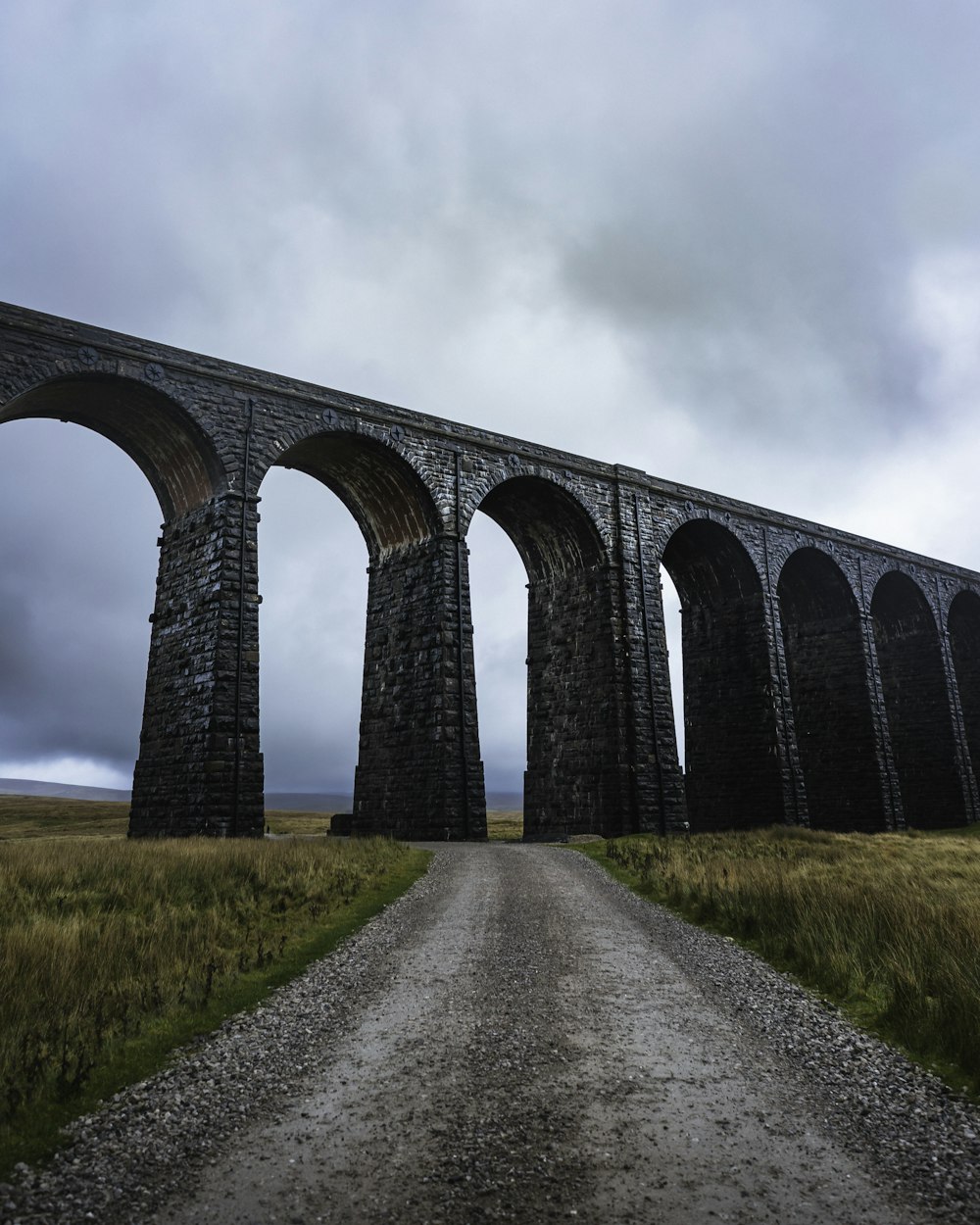 a long stone bridge over a gravel road