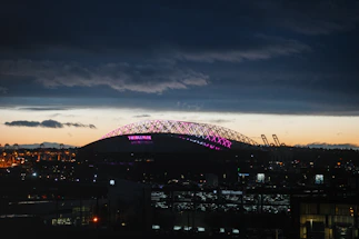 A sleek neon-lit football stadium at night with glowing blue and purple accents.
