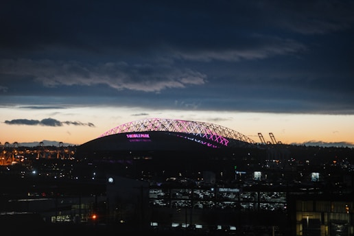 A vibrant neon blue and violet football stadium under night sky with glowing glassmorphism effects.