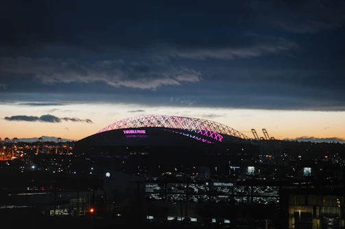 A sleek neon-lit football stadium at night with glowing blue and purple accents.