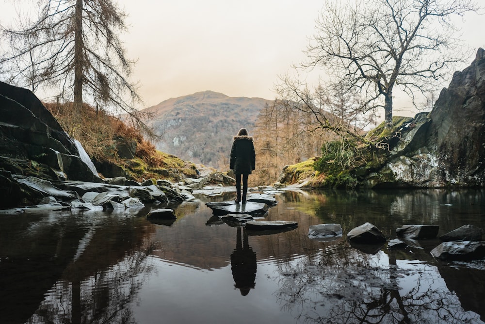 a person standing on a rock in the middle of a river