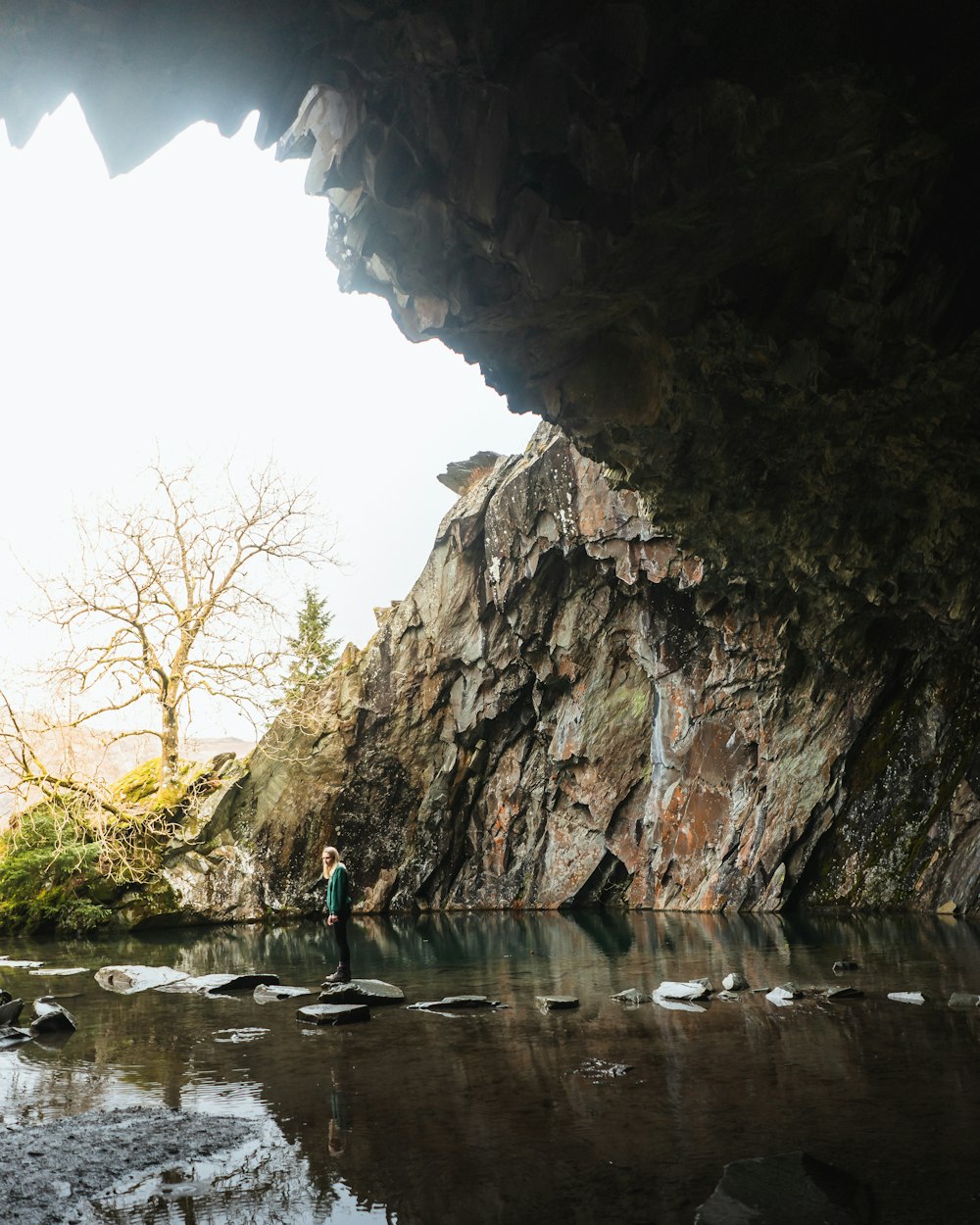 a man standing in a cave next to a body of water