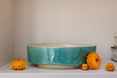 An elegant light orange ceramic vase displayed on a simple white shelf.