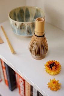 Close-up of a decorative accent shelf featuring handcrafted pottery and a small stack of colorful books.