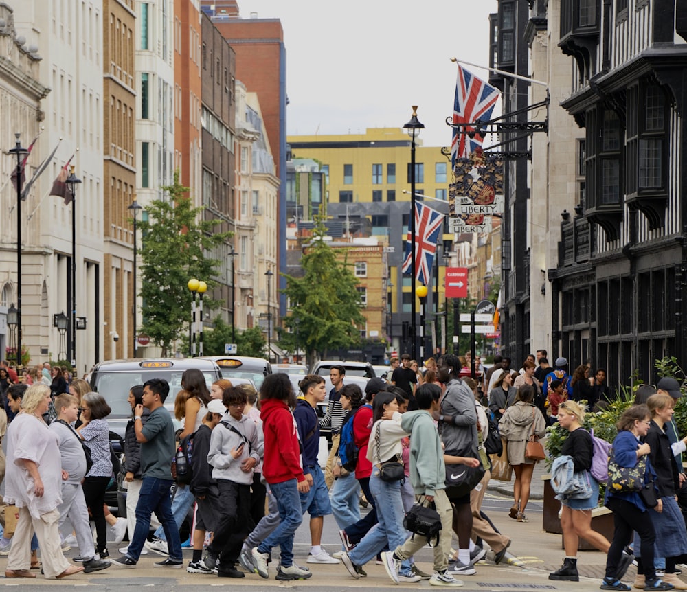 uma multidão de pessoas atravessando uma rua em uma cidade