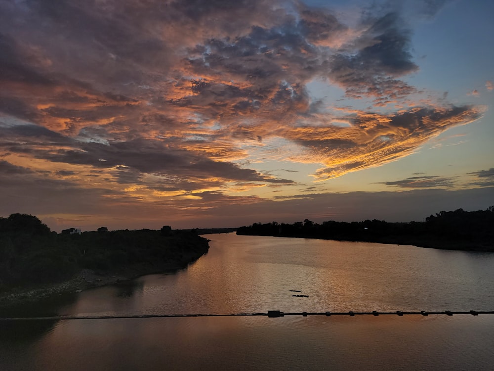 a body of water with a sky filled with clouds