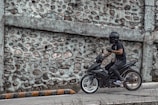 A rider putting on a helmet next to a matte black motorbike ready to hit the road.