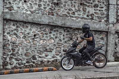 A rider putting on a helmet next to a matte black motorbike ready to hit the road.