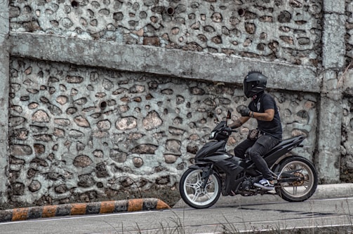 A rider wearing a helmet on a black motorcycle cruising on a highway.