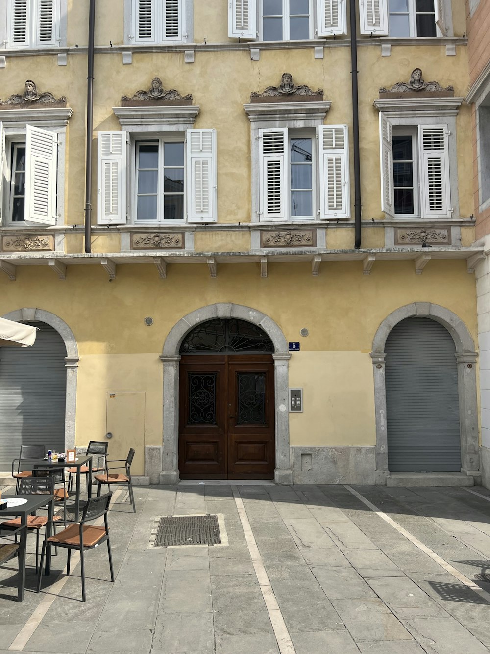 a yellow building with white shutters and a brown door