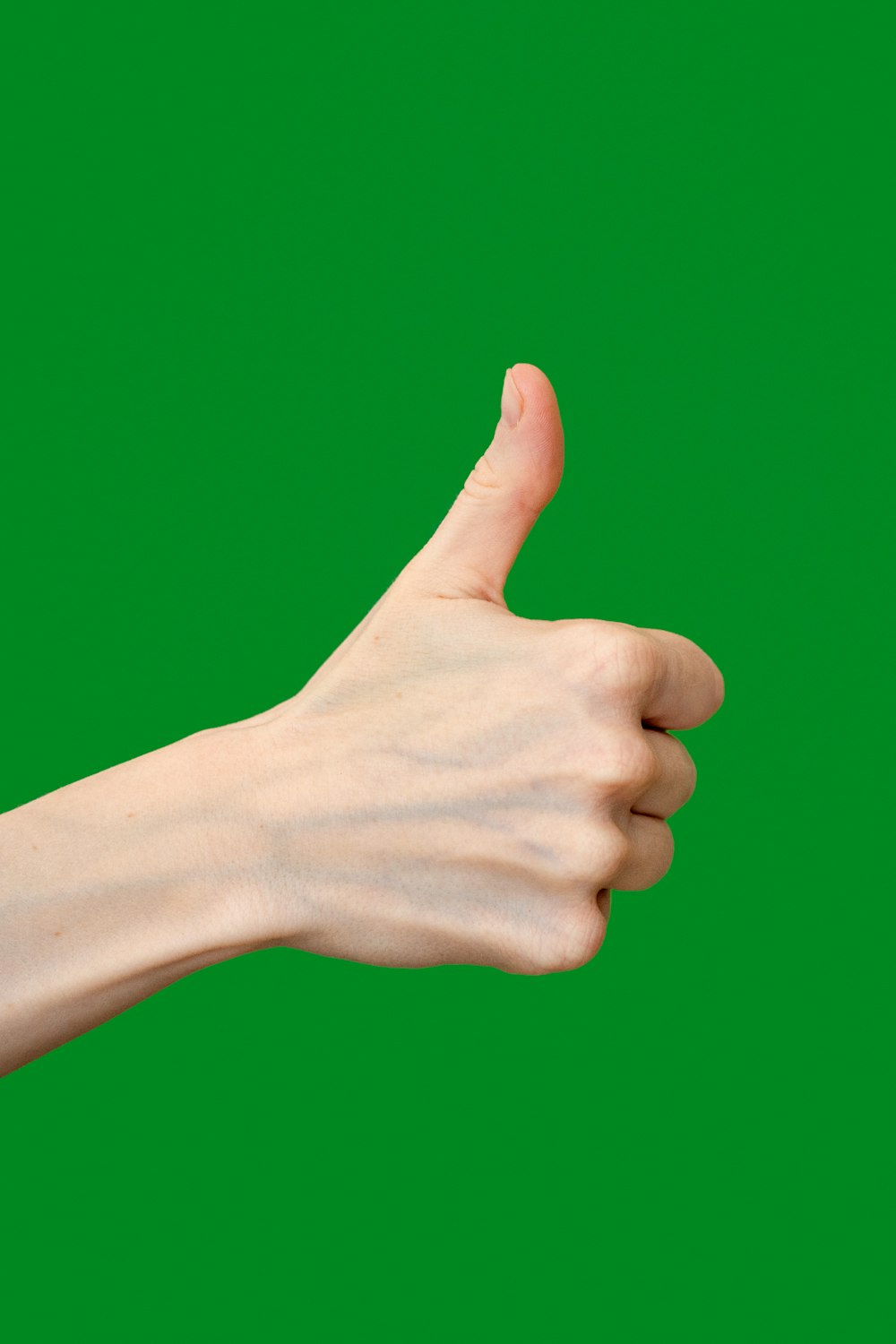 eine Hand, die ein Daumen-hoch-Zeichen vor grünem Hintergrund gibt
