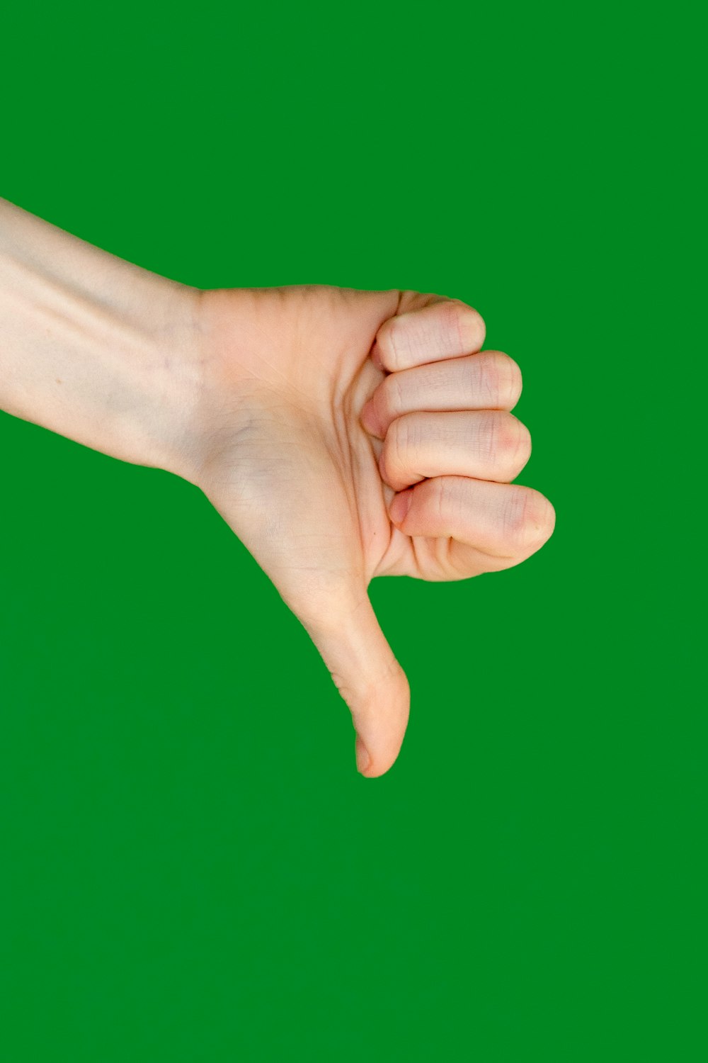 Die Hand einer Person, die ein Mobiltelefon vor grünem Hintergrund hält