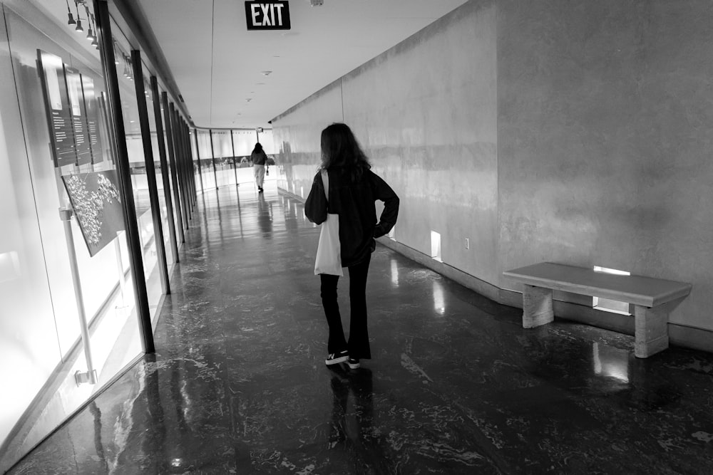 a woman standing in a hallway next to a bench