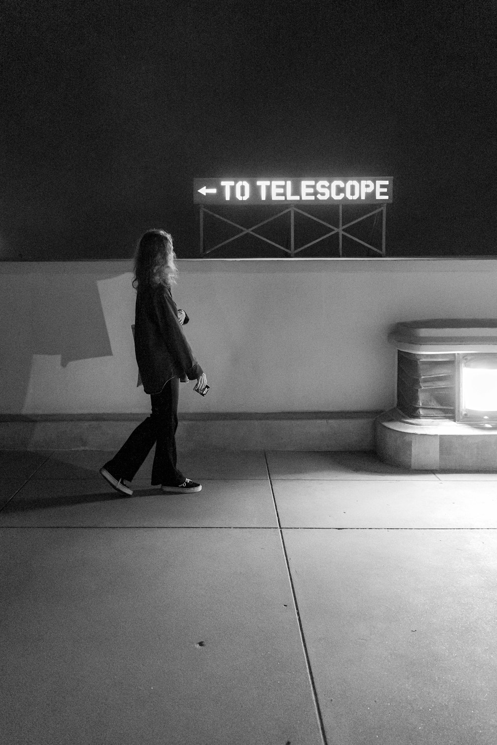 a woman walking past a sign that reads to telescope
