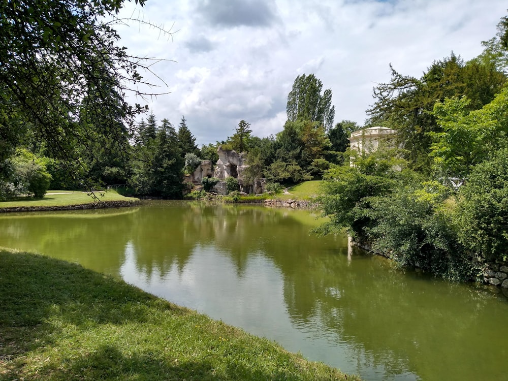 a pond in a park with a house in the background