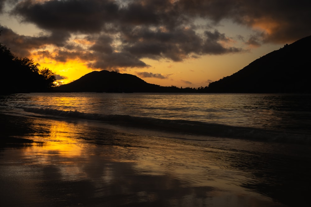 a sunset on a beach with a mountain in the background