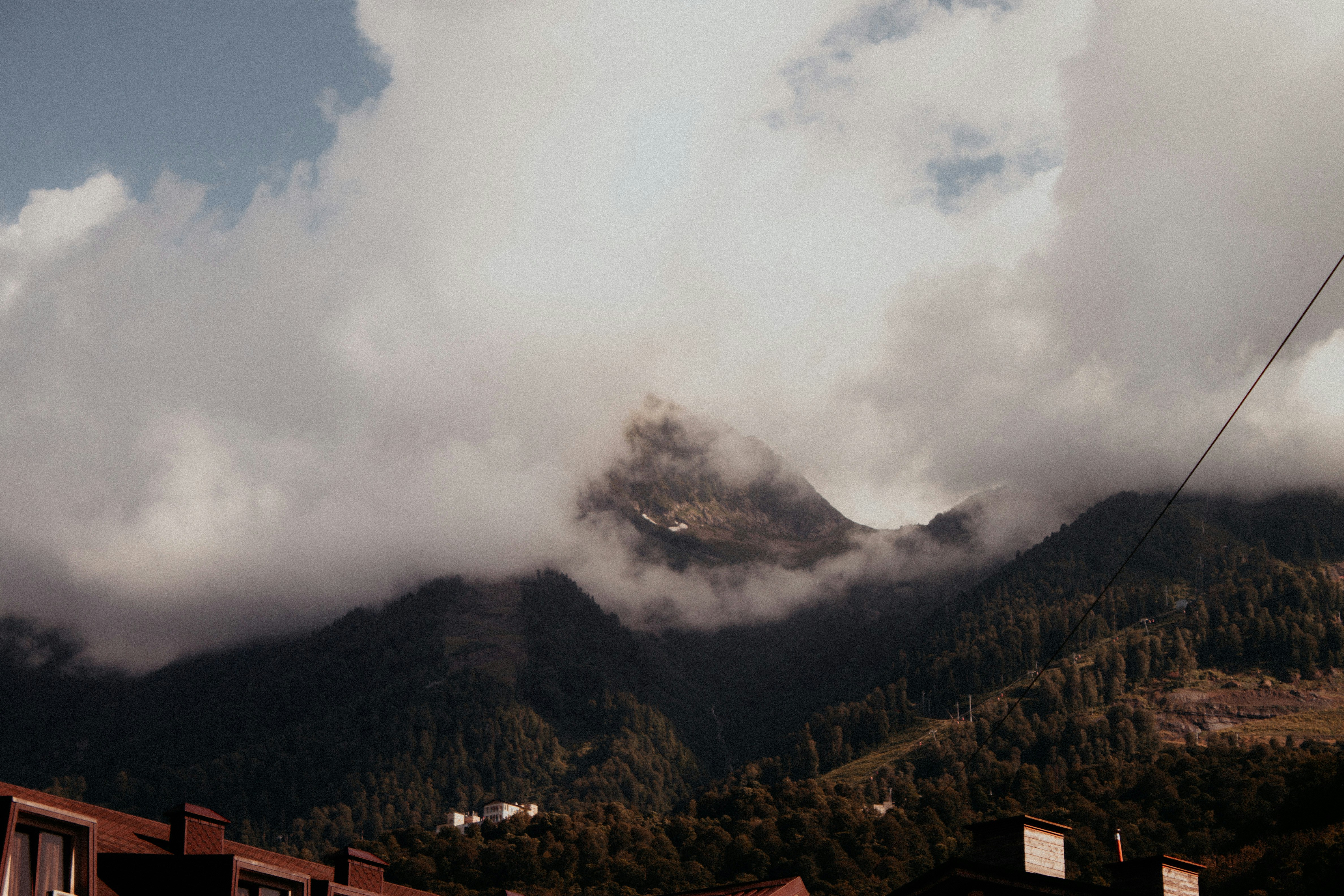 a view of a mountain range with clouds rolling over it
