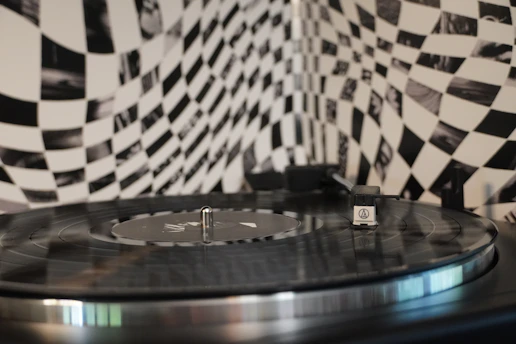 A striking black-and-white photo of a vinyl record spinning under a spotlight, edges fading into deep black.