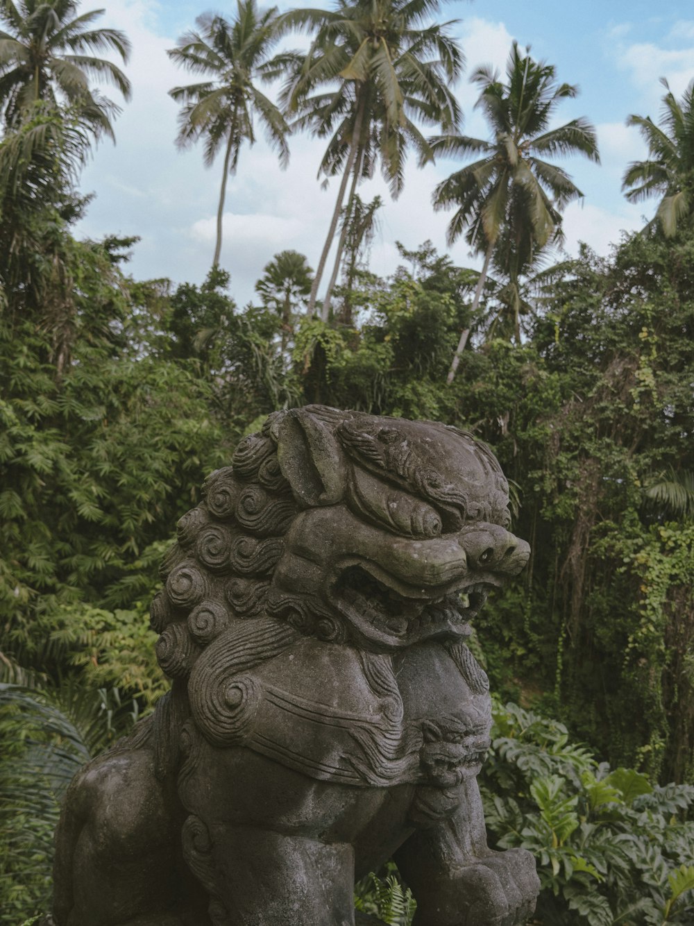 a statue of a lion in front of some trees