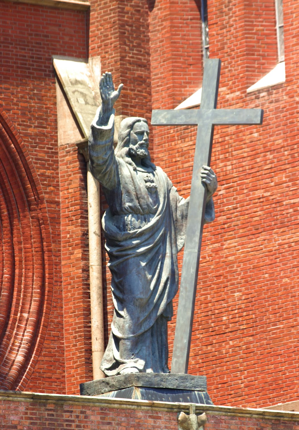 a statue of jesus holding a cross on top of a building