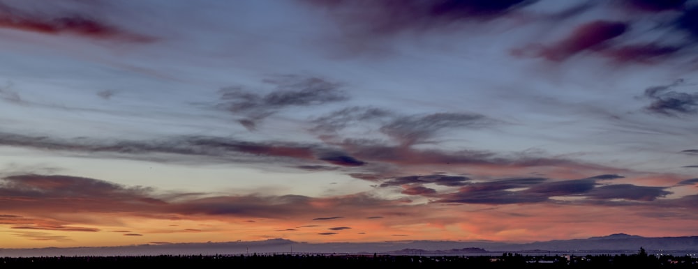 a plane flying in the sky with a sunset in the background